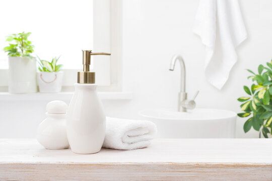 Soap Dispenser With Shampoo And Towel On Defocused Bathroom Background