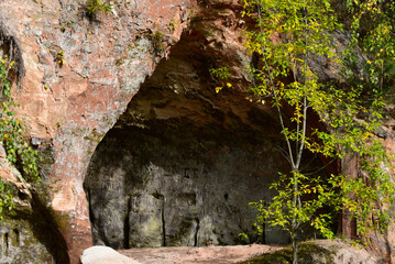 .red rock in nature park with hole surrounded by trees