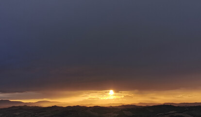 hdr Il sole al tramonto illumina le montagne in un cielo di nuvole nere