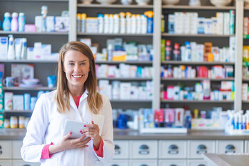 Smiling pharmacist chemist woman standing in pharmacy drugstore, looking at camera. Medicine,...