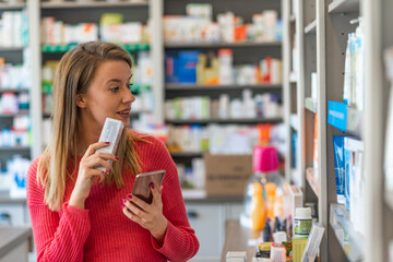 Woman uses smart phone while in pharmacy. They have the best medicine here. They have so much on...