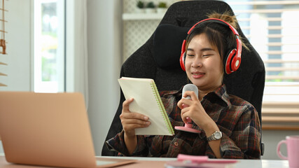 Cheerful young woman wearing headphone recording an internet podcast for social media channel
