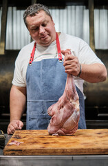 A butcher butchers a leg of lamb for grilling. Pitmaster prepares meat for smoking