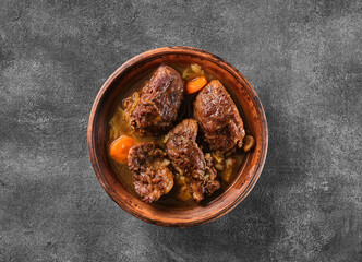 Traditional German braised pork cheeks in brown sauce with carrot as closeup.