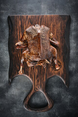 Smoked whole duck on a wooden board.