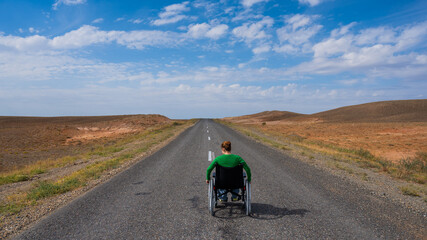 Woman in a wheelchair on a highway in the steppes. 