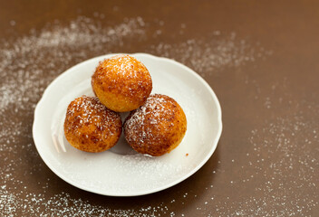 Fototapeta Donuts with powdered sugar on a white plate on a brown background. obraz