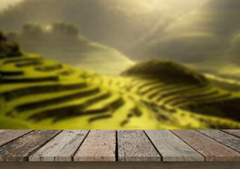 Wooden table top on blur rice field and mountain background in daytime.Harvest rice or whole wheat.For montage product display or design key visual layout.View of copy space.