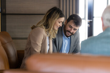 Young couple looking to buy a new car. Car salesman making a sale. Signing a papers for purchase a new car