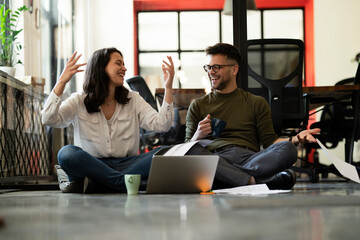 Colleagues in office. Businesswoman and businessman sitting on the floor. Colleagues working on the project