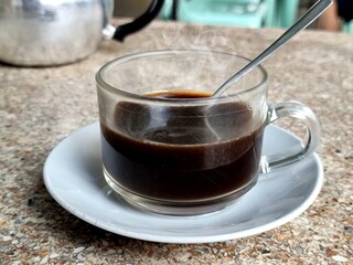 hot black coffee in a clear glass Placed near the kettle on a marble table. At a vintage coffee shop in southern Thailand
