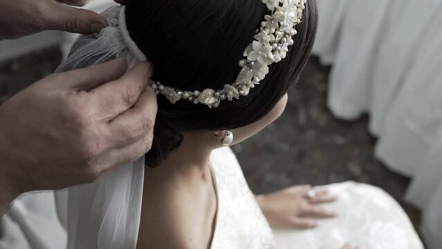 Decorating the bride diadem with a white, thin cloth, close up view from above