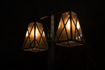 Two retro style lamps with bright yellow light against the dark night background. Vintage outdoors...