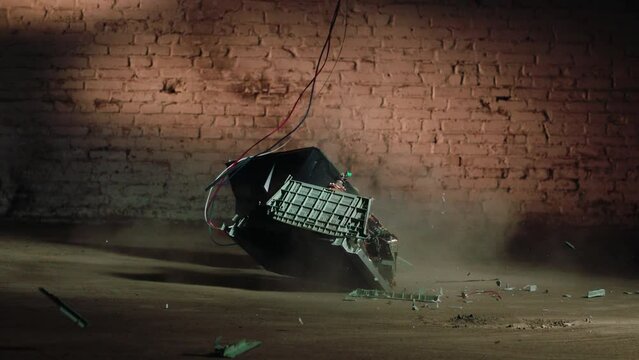 an old tube TV breaks on a concrete floor against a brick wall