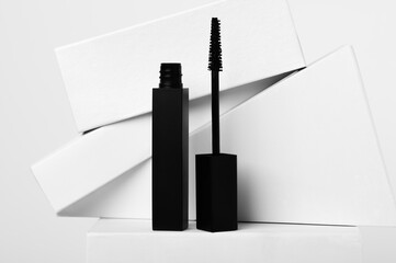 Black mascara and brush with geometric shapes on white background. Luxury cosmetic product for eyes makeup. Beauty and fashion industry