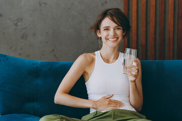 Young woman wears white tank shirt hold drink clear fresh pure still water from transparent glass...