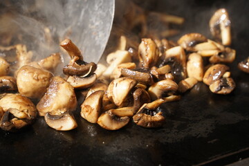 Roasting mushrooms on an open outdoor flat plate.