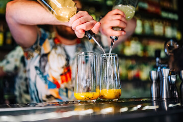 bartender making cocktail with passion fruit in a nightclub bar