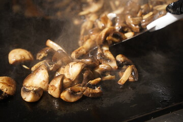 Roasting mushrooms on an open outdoor flat plate.