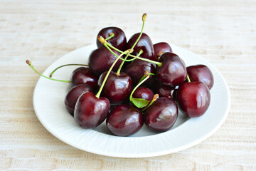 dark ripe cherries on white plate isolated, close-up