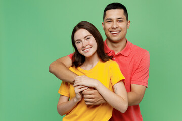 Naklejka premium Young cheerful fun happy adorable couple two friends family man woman 20s wear basic t-shirts together boyfriend hug girlfriend isolated on pastel plain light green color background studio portrait