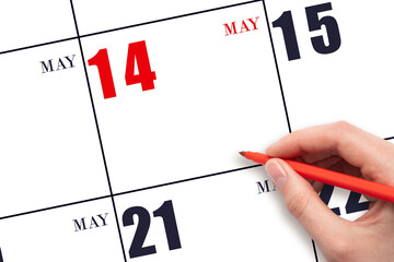 A hand holding a red pen and pointing on the calendar date May 14. Red calendar date, copy space,...