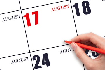A hand holding a red pen and pointing on the calendar date August 17. Red calendar date, copy...