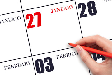 A hand holding a red pen and pointing on the calendar date January 27. Red calendar date, copy...