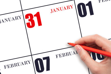 A hand holding a red pen and pointing on the calendar date January 31. Red calendar date, copy...