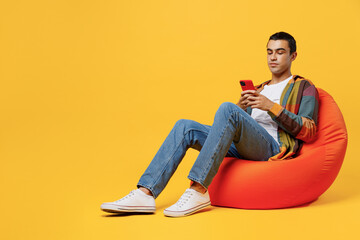 Full body young middle eastern man he wear casual shirt white t-shirt sit in bag chair hold in hand...