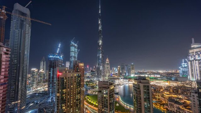 Panorama of Dubai Downtown cityscape with tallest skyscrapers around aerial day to night transition timelapse. Construction site of new towers and busy roads with traffic from above
