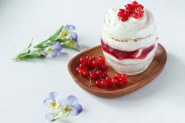 Trifl in a glass of red currants on a wooden plate.