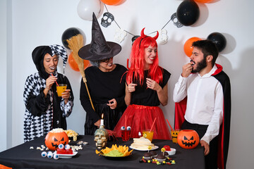 Four people talking and laughing at a costume Halloween party in a house.