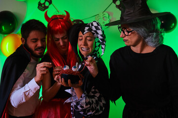 Four people look disgusted at a candy worms at a costume Halloween party.