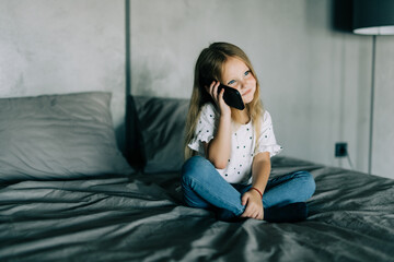 little girl on bed with cell phone at home