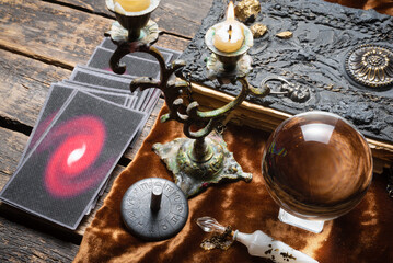 Tarot cards, crystal ball and magic book on the old fortune teller desk table background. Future...