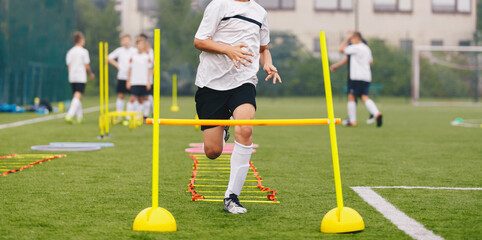 Young boy jumping over ladder and pole at a soccer training session. Young footballers on the junior football team improving agility and strength. Soccer practice for youth
