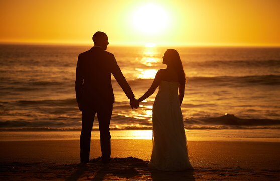 Love, summer and couple at a beach at sunset, silhouette holding hands and bonding with ocean views in nature. Romance, travel and nature with man and woman enjoying sea honeymoon and romantic trip
