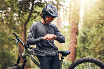 Time, bicycle and man cycling in nature checking his stopwatch in a cardio workout, training and exercise outdoors. Fitness, forest and healthy person proud of his bike riding in the natural woods - obrazy, fototapety, plakaty