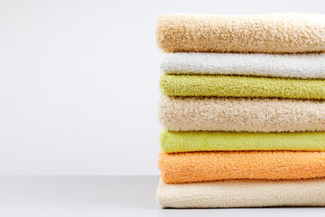 A stack of clean towels on a light gray background. Cotton towels on table. Space for text