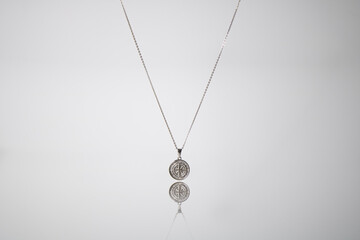 silver pendant with a chain against a white backdrop product picture adverstisement