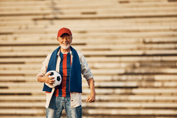 Portrait of happy senior soccer fan outdoors looking at camera. Copy space.