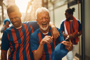 Happy senior sports fan and his son laugh and have fun during soccer world cup.