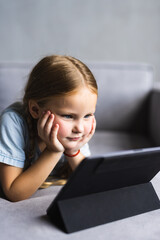 Focused cute preschooler girl watching movie, animated films, cartoons on tablet computer. Child...