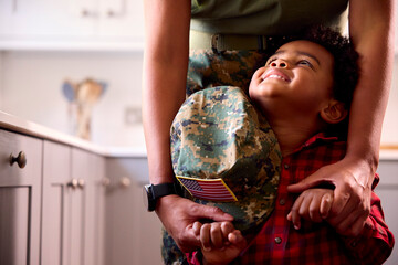 Close Up Of American Army Mother In Uniform Home On Leave With Son Holding Her Cap In Family Kitchen