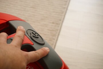 Closeup of man's fingers pushing black and white vacuum cleaner's cable rewind button