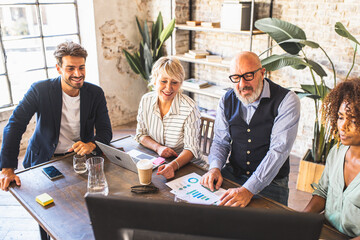 Mature male entrepreneur of fashion business explaining to colleagues the marketing strategy of the new company, multi-ethnic working group with men and women of different ages