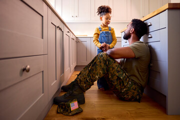 Daughter Comforting Depressed Father In Uniform Suffering With PTSD Sitting On Floor On Home Leave