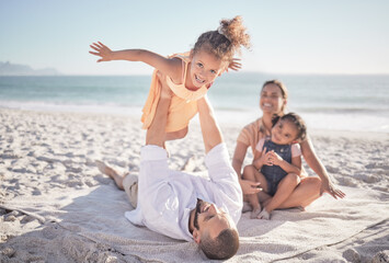 Family, children and playing with a girl on a beach holiday with her parents and sister during summer. Kids, travel and ocean with a female child or daughter on the sand by the sea with her father