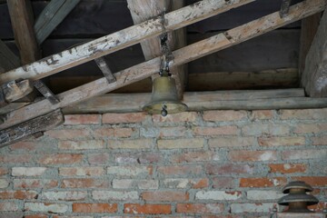 Iron bell hanging from a wooden construction in an old brick building - Powered by Adobe